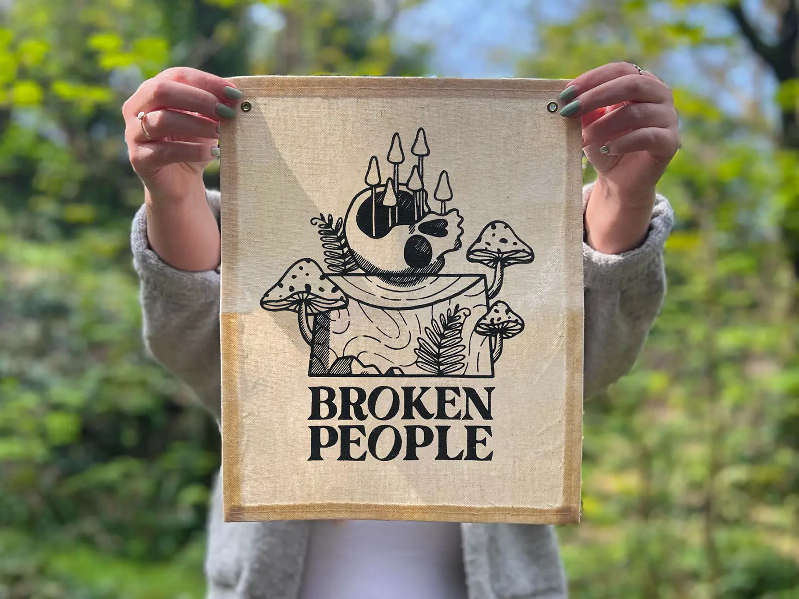 Broken People Banner on canvas, held up in the woods to show scale.